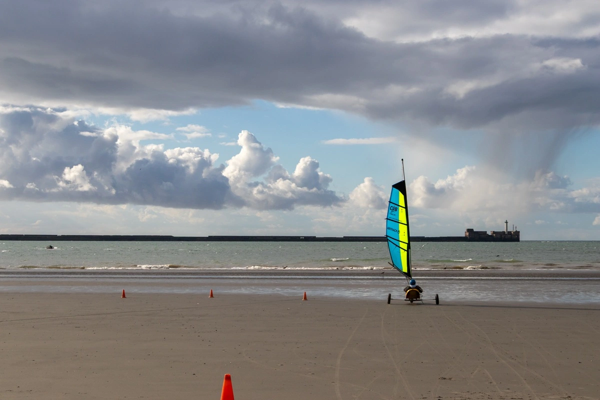 char a voile sur la plage de boulogne sur mer avec un ciel nuageux et la digue en arrière plan