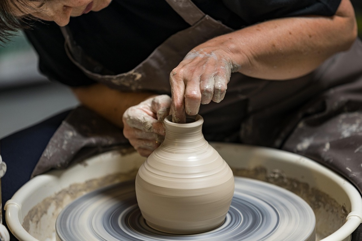 Artisan en plein travail, façonnant un objet traditionnel avec des outils manuels dans un atelier lumineux